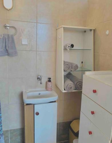 a bathroom with a sink and a cabinet with towels at Ground floor apartment with gym & yard in Paggaio in Próti