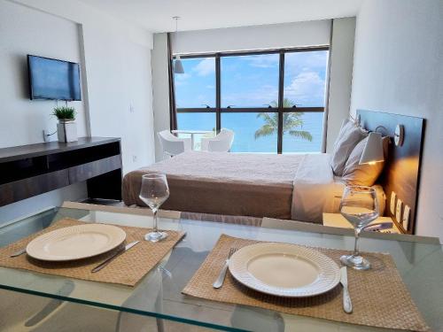 a bedroom with a bed and a table with plates and glasses at Flat Frente Mar + Limpeza | R601 in Maceió