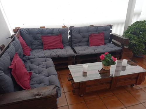 ein Wohnzimmer mit Sofas und einem Tisch mit roten Kissen in der Unterkunft Apartamento completo en Sierra Sur in Villanueva de San Juan