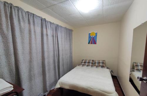 a small bedroom with a bed and a curtain at Hakuna Matata in Cuenca