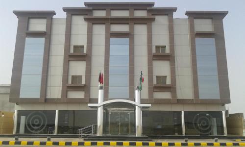 a building with two flags in front of it at Desert Palm Aparthotel in Al Nairyah