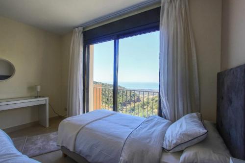 een slaapkamer met een bed en een groot raam bij 1090 amazing panorama sea view penthouse large terrace heated pool gym in Marbella