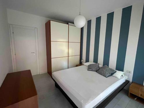 a bedroom with a white bed with blue and white stripes at Casa Lavagna giardinetto in Lavagna