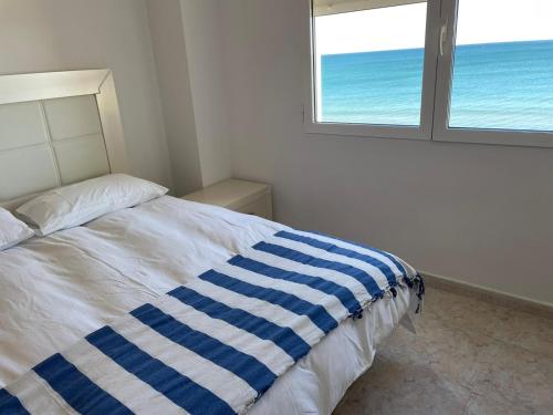 1 dormitorio con 1 cama con manta de rayas azul y blanco en Apartamento con Vistas Panorámicas, en Sueca