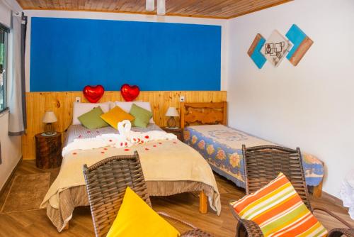 um quarto com uma cama e duas cadeiras em Chalé Lírio Cachoeira do Vale em Monte Verde
