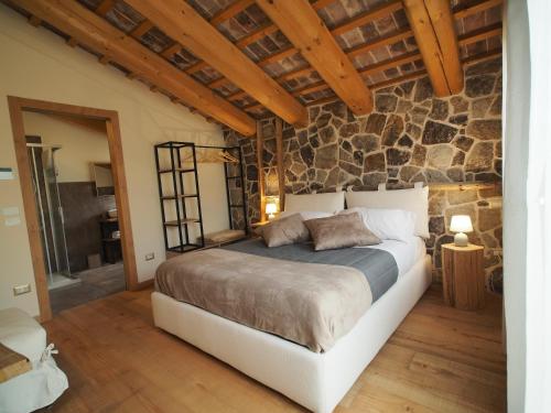 a bedroom with a bed and a stone wall at AZIENDA AGRICOLA CA' LUNGA in Cinto Euganeo