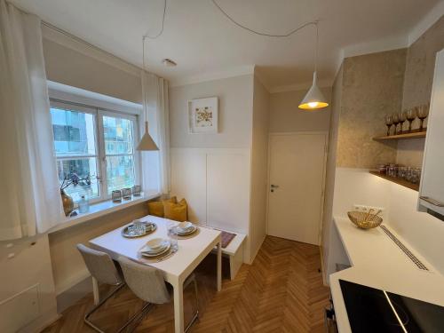 een kleine keuken met een witte tafel en stoelen bij Golden Flat by GrazRentals with parkview - brandnew & free parking in Graz