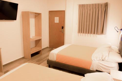 a hotel room with a bed and a tv and a bedroom at Hotel Yivinaca in Barranquilla