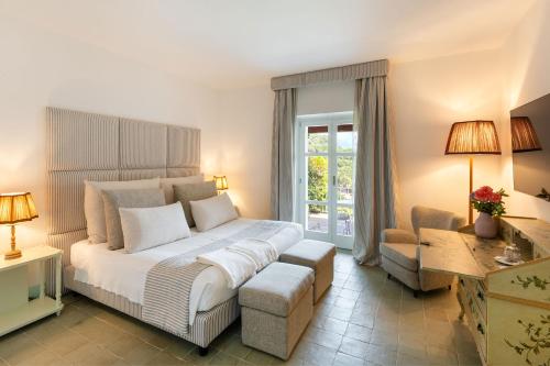 una camera con un grande letto bianco e una sedia di Santavenere Hotel a Maratea