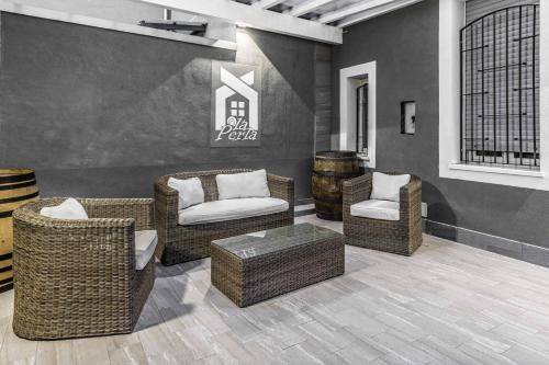 a lobby with wicker chairs and chairs and a table at La Perla Rooms in Saronno