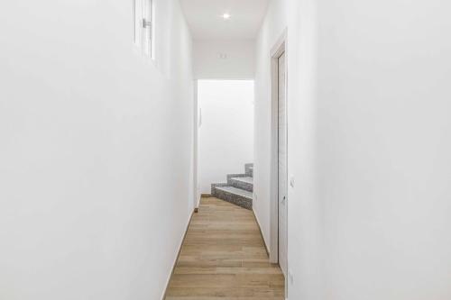 a hallway with white walls and wooden floors at La Perla Rooms in Saronno