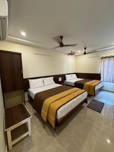 a bedroom with two beds and a table at HOTEL DKR GRAND in Tirupati