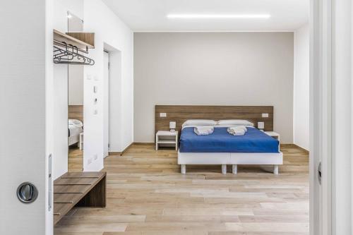 a bedroom with a bed with blue sheets and wooden floors at La Perla Rooms in Saronno