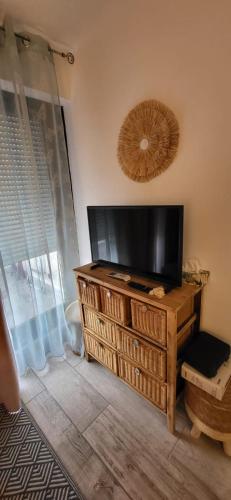 Elle comprend une télévision à écran plat installée au-dessus d'une commode en bois. dans l'établissement Terrasses 2 - Plage et commerces à 400 m, au Grau-du-Roi