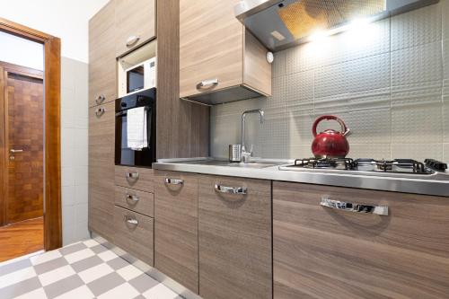 a kitchen with wooden cabinets and a red tea kettle at Amazing Art Déco Apartment Pantheon - TopCollection in Rome