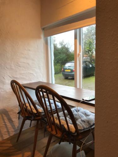 a dining room table with two chairs and a window at Tiny Cosy Snug in Pembrokeshire