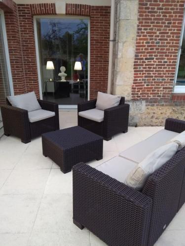 d'une terrasse avec quatre chaises en osier et une table. dans l'établissement gite la fécampoise près de Fécamp, à Ganzeville