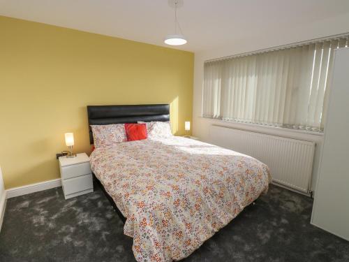 a bedroom with a bed and a yellow wall at Cosmic Pearl in Garforth