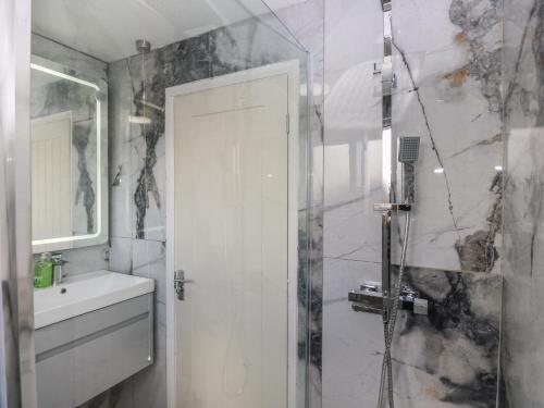 a white bathroom with a shower and a sink at Cosmic Pearl in Garforth