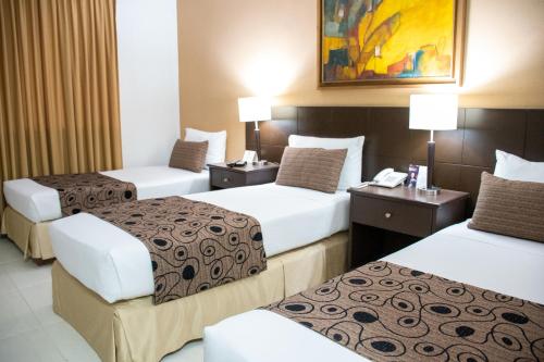 a hotel room with three beds and two lamps at Hotel Arizona Suites Cúcuta in Cúcuta