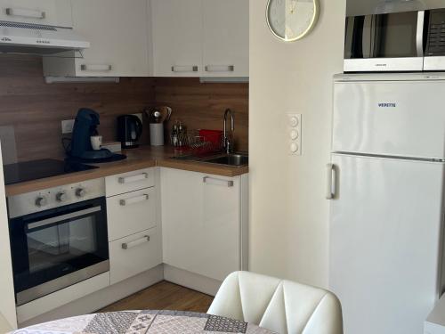 a kitchen with white appliances and a white refrigerator at Studio cocooning cap d’Agde in Cap d'Agde