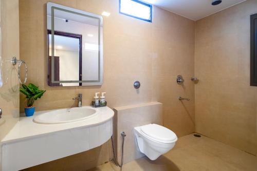 a bathroom with a sink and a toilet and a mirror at Monday Hotels Swarna's The Capital in Vijayawāda