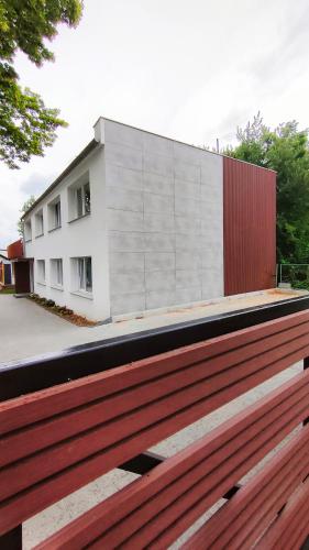 a building behind a wooden bench in front of a building at APARTAMENTY Charzykowy in Charzykowy