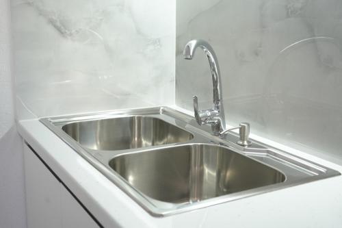 a stainless steel sink in a white kitchen at SHANO'S Apartment - Free Parking in Sarandë