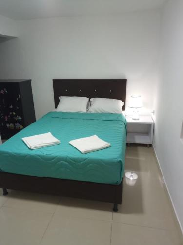 1 dormitorio con 1 cama con 2 toallas en Habitaciones en apartamento central, cerca de sitios turísticos Jardín Botánico y metro estación universidad, en Medellín