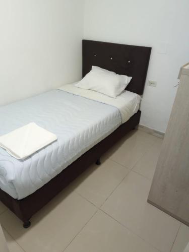 a bed in a room with a white floor at Habitaciones en apartamento central, cerca de sitios turísticos Jardín Botánico y metro estación universidad in Medellín