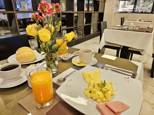 una mesa con un plato de comida y zumo de naranja en Inkari Apart Hotel, en Lima