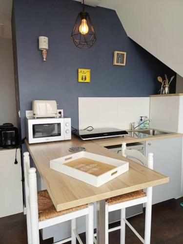 - une cuisine avec une table, un four micro-ondes et un évier dans l'établissement La maison bleue, entre terre et mer, à Plougastel-Daoulas