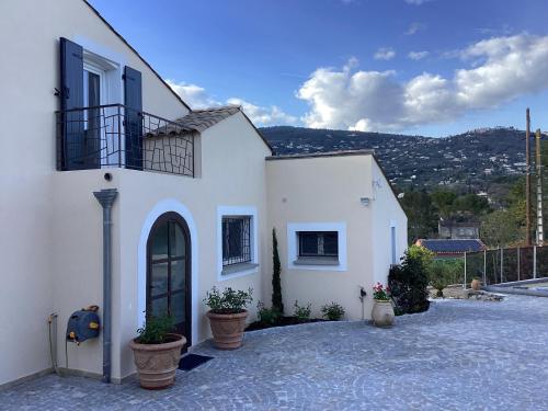 une maison blanche avec des plantes en pot devant elle dans l'établissement Mas Madilauric 2 BNB, à Peymeinade