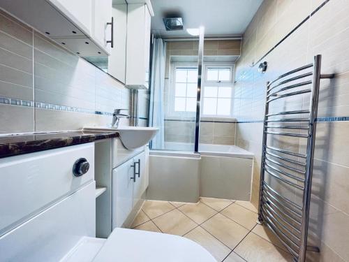 ein Badezimmer mit Waschbecken, Badewanne und Toilette in der Unterkunft Stylish townhouse-Sleeps 9-Free parking in Milton Keynes