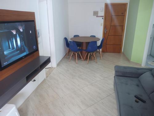 a living room with a table and chairs and a television at Apartamento Vista Mar Praia Grande, Ocian in Praia Grande