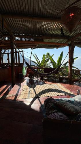 a hammock on a patio with a view of the ocean at Earthship 3 levels FAMILY apartment with lake view in San Marcos La Laguna