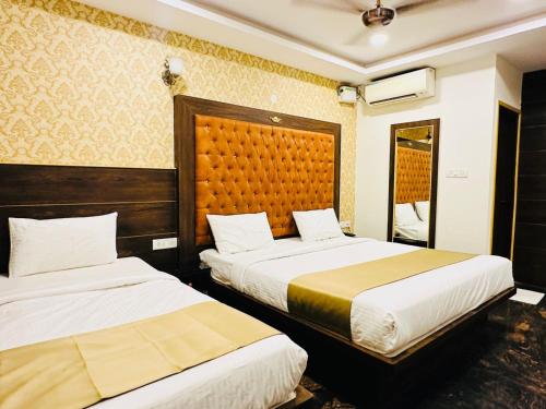 a hotel room with two beds and a mirror at Hotel Classio Koramagala in Bengaluru