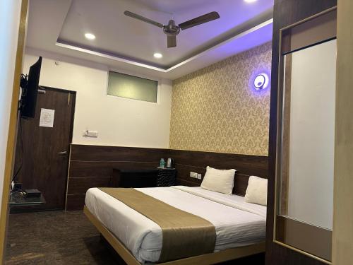 a bedroom with a bed with a ceiling fan at Hotel Classio Koramagala in Bengaluru