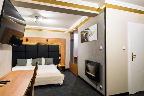 a bedroom with a bed and a desk and a tv at GLAMOUR - Restaurant & SPA in Przeźmierowo