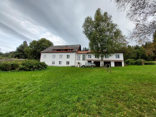 a white house with a car in a field at U Dvou rysů in Zdíkov