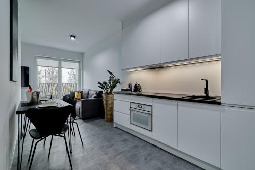 a kitchen with white cabinets and a table and a couch at Apartament Sztuk Pięknych 4 in Piła