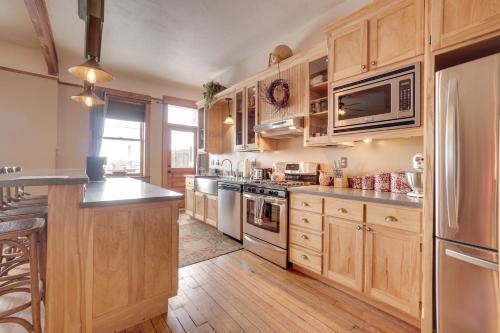 a kitchen with wooden cabinets and stainless steel appliances at Vintage Downtown Laramie Apartment with Deck! in Laramie