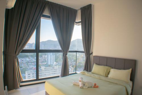 a baby doll laying on a bed in front of a window at Prime Comfort Seaview with Netflix and Water Filter near Georgetown in Jelutong