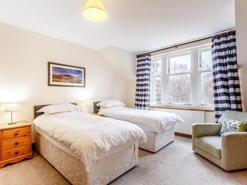 a bedroom with two beds and a chair and a window at 6 Bed in Lairg CA210 