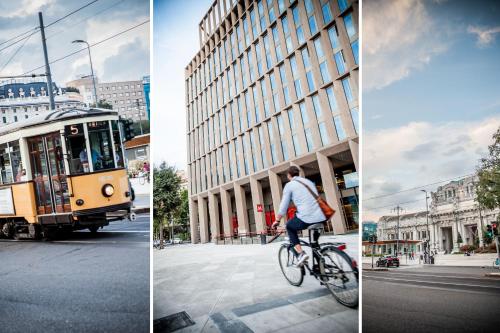 a man riding a bike on a city street with a streetcar at Glam Milano in Milan