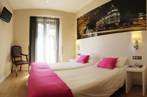 um quarto de hotel com uma cama grande e almofadas cor-de-rosa em CH Olmedo em Madrid