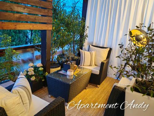 eine Terrasse mit Korbstühlen, einem Tisch und Pflanzen in der Unterkunft Apartment Andy in Medvode