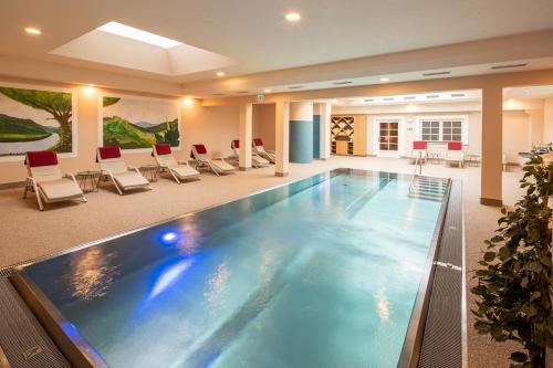 a large swimming pool in a hotel lobby with chairs at Hotel Zum Schwarzen Bären in Emmersdorf an der Donau