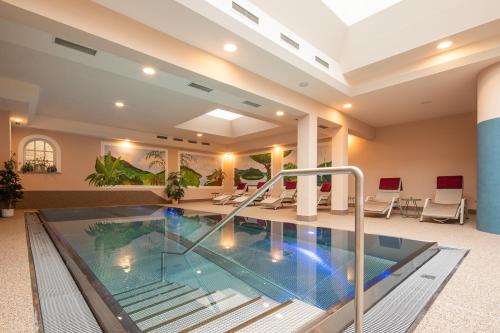 a large indoor swimming pool in a lobby with chairs at Hotel Zum Schwarzen Bären in Emmersdorf an der Donau
