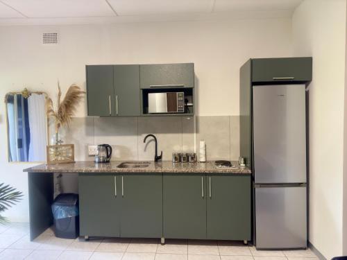 a kitchen with green cabinets and a refrigerator at Busa House in White River